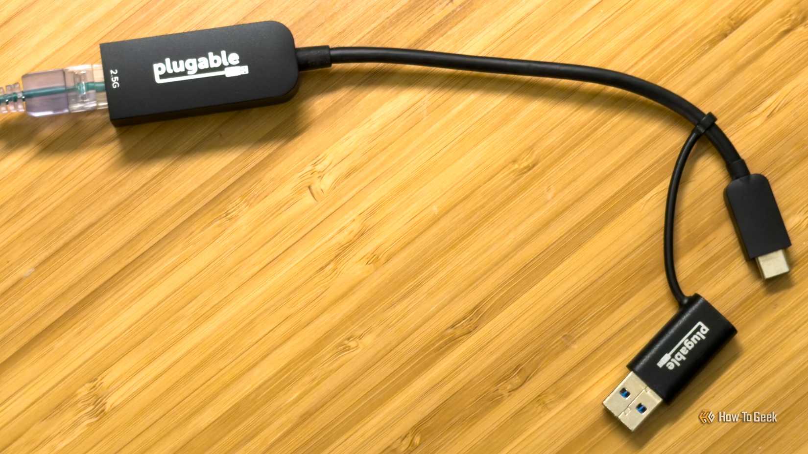 O adaptador plugável USB-C/A para Ethernet 2,5G colocado em uma mesa de bambu.