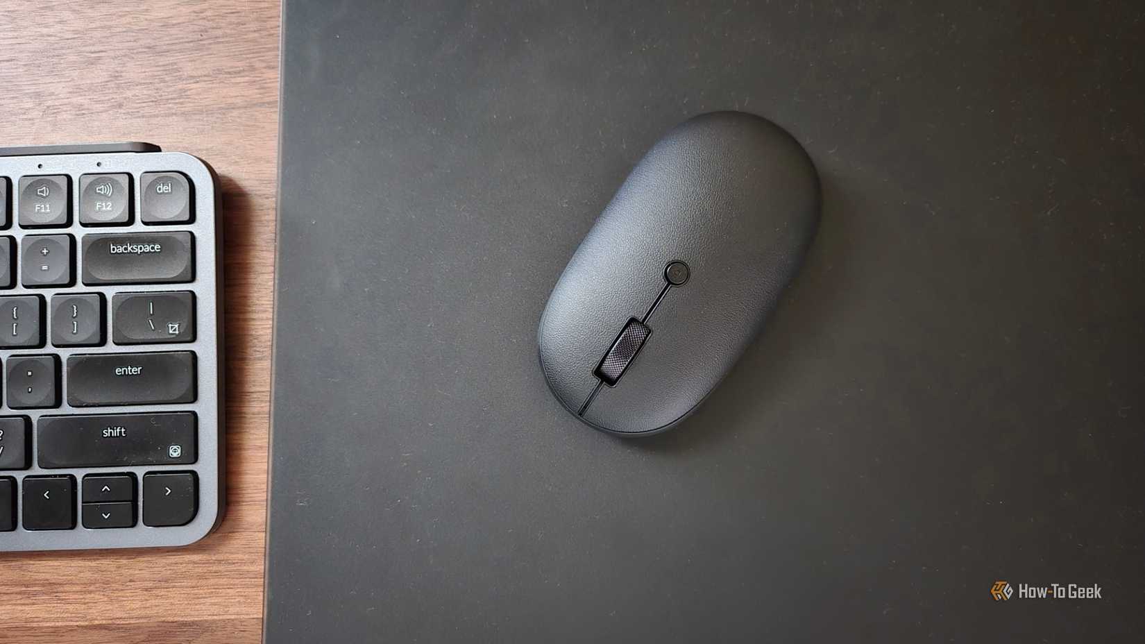 Mouse Bluetooth Satechi OntheGo em um mouse pad de vidro temperado próximo a um teclado