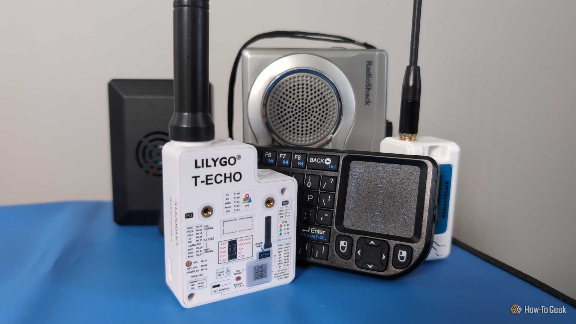 Several small electronic devices including LoRa radios, a mini keyboard, a cassette recorder, and a Raspberry Pi computer.