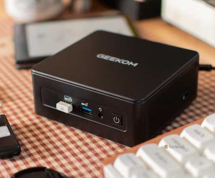 The GEEKOM IT15 mini PC on a desk with a keyboard and ereader.