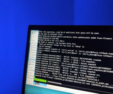 A Kubuntu Focus laptop screen with the Yakuake terminal emulator for Linux visible and an APT package manager ugprade in progress.