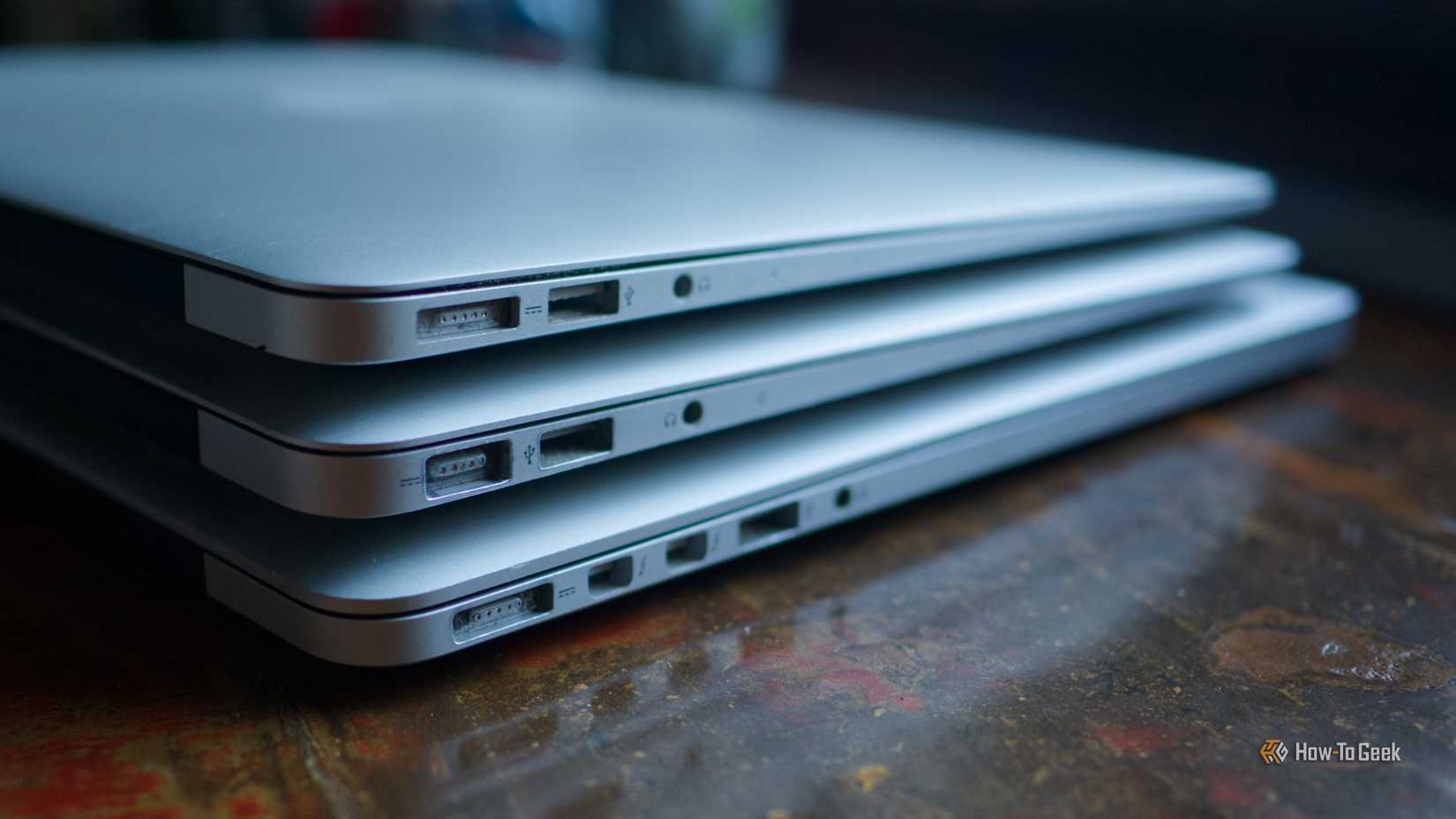 A stack of old MacBook Air and MacBook Pro laptops.