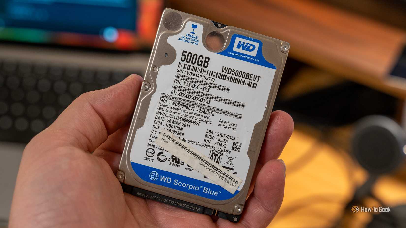 A 500GB Western Digital WD Blue 2.5-inch hard drive being held in a hand.