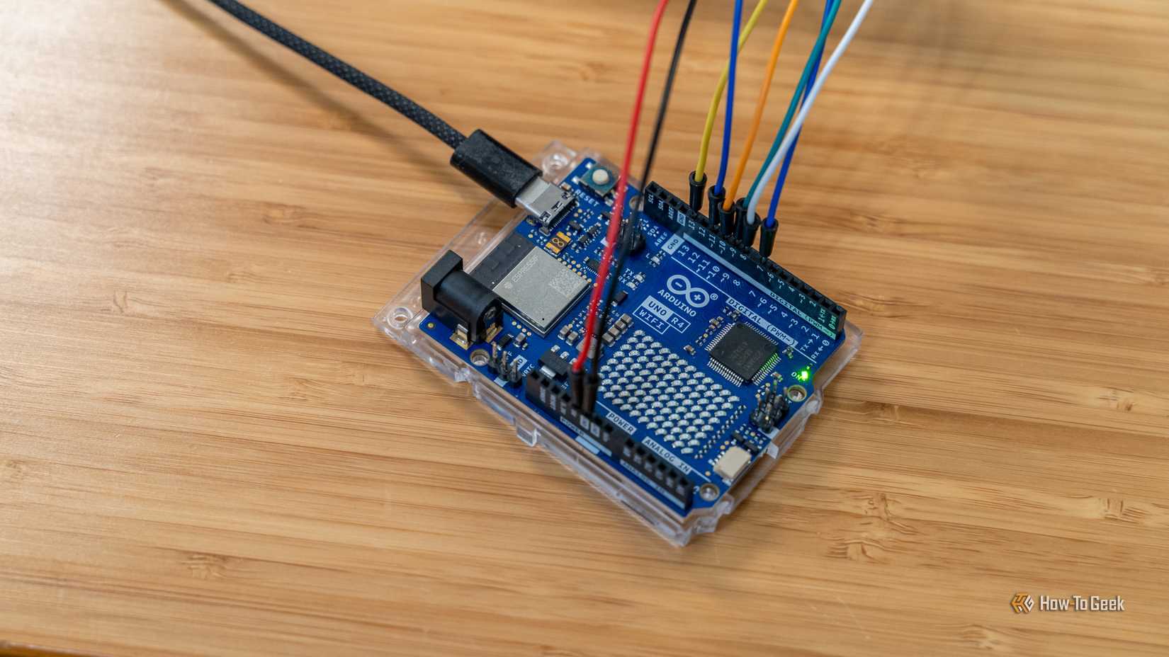 Um microcontrolador Arduino R4 WiFi com cabos jumper e um cabo USB-C conectado.