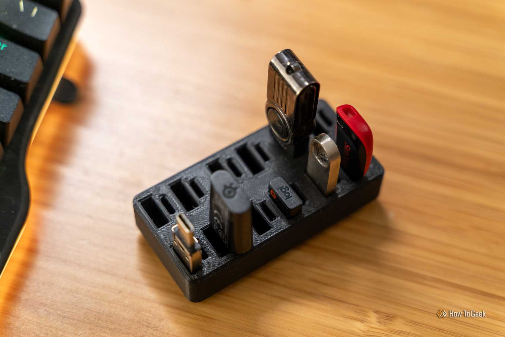 A 3D printed USB organizer with USB drives in it on a wooden desk.