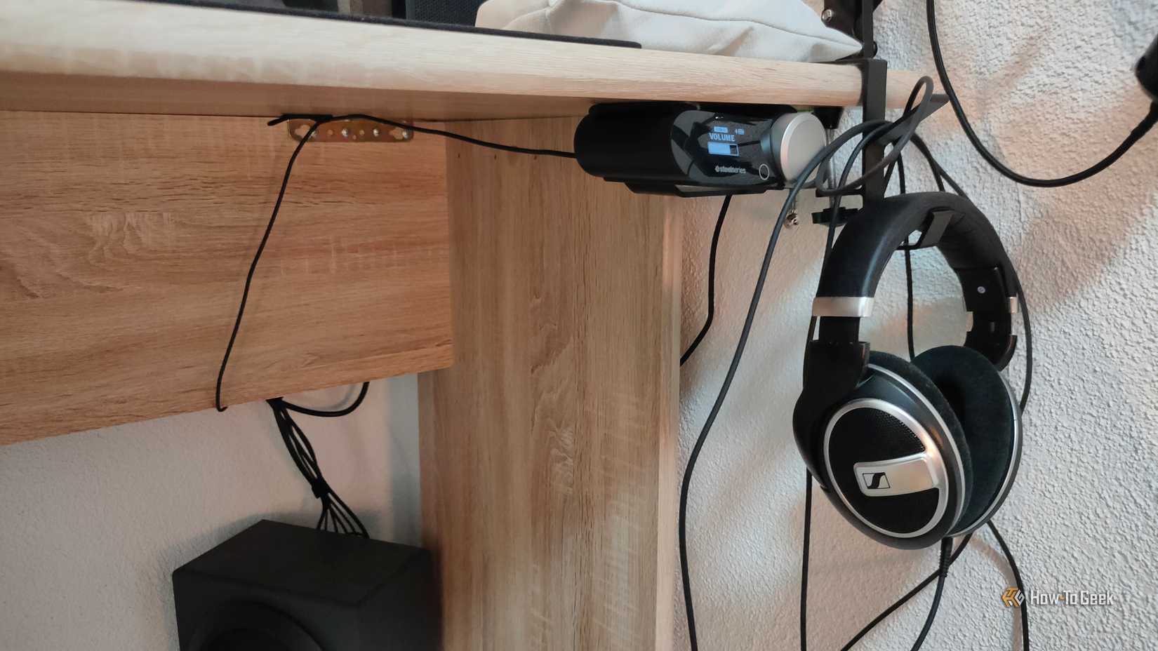 A headset receiver mounted underneath the desk with a pair of headphones next to it.
