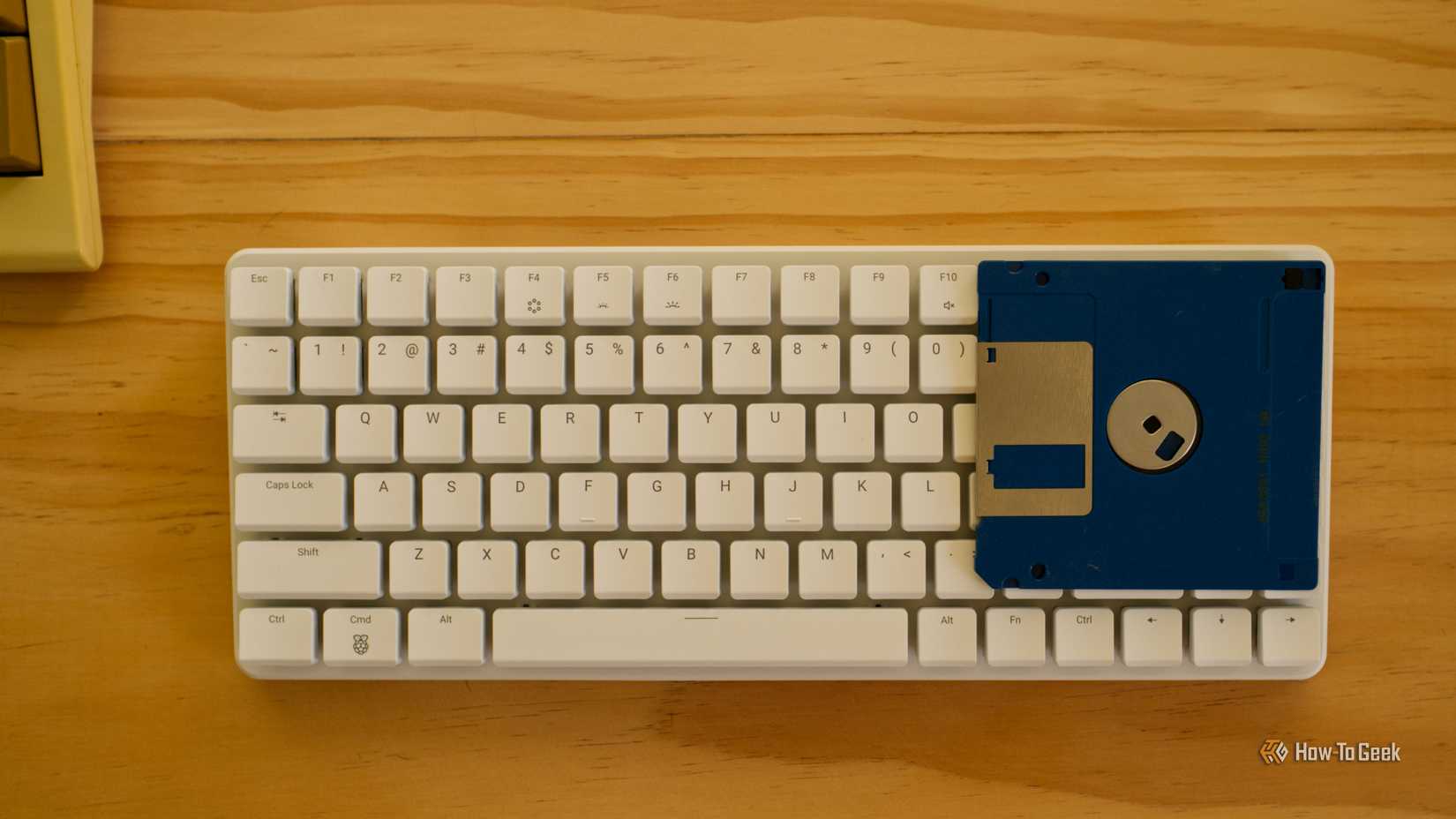 Raspberry Pi 500+ with a floppy disk for scale.