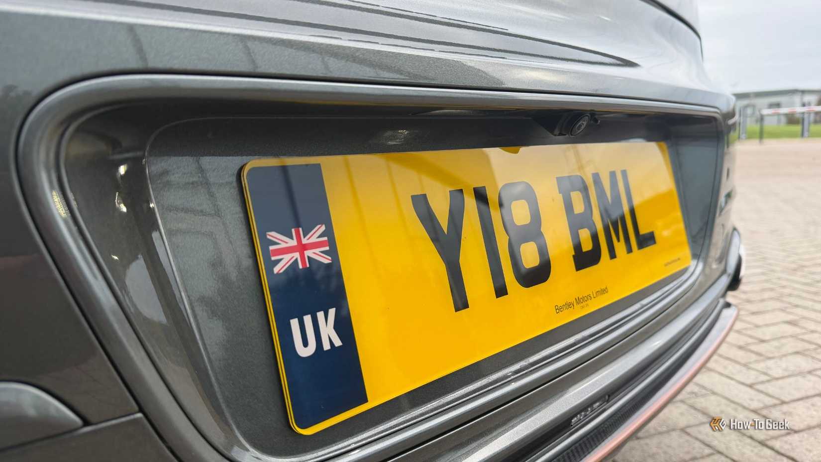 Крупный план номерного знака и камеры заднего вида на Bentley Flying Spur Speed ​​2026 года выпуска.