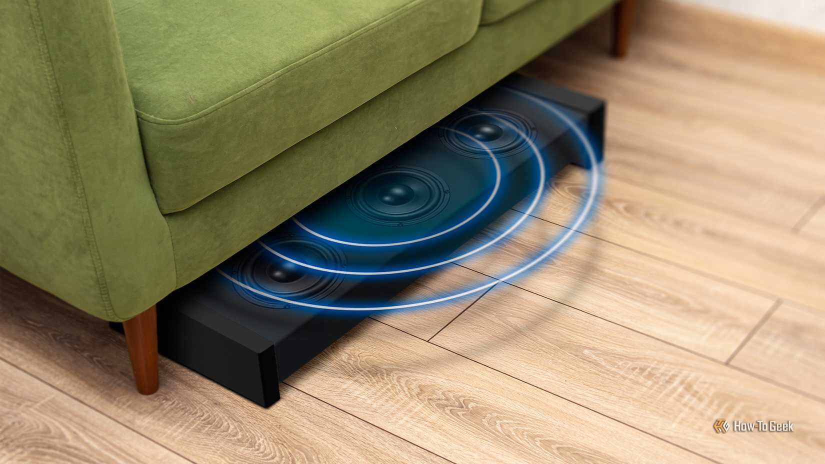 A subwoofer peaking out from under a couch.