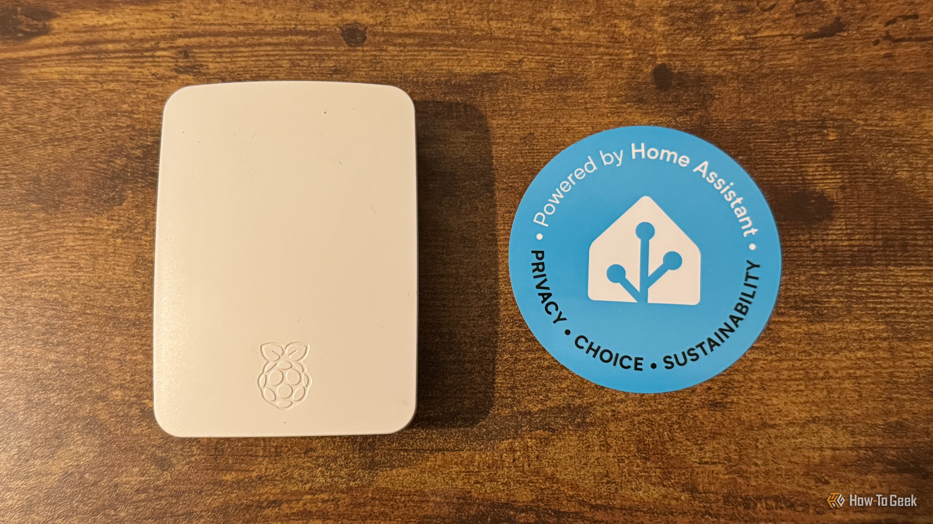 A Rasbperry Pi in an official Raspberry Pi case next to a Home Assistant sticker.