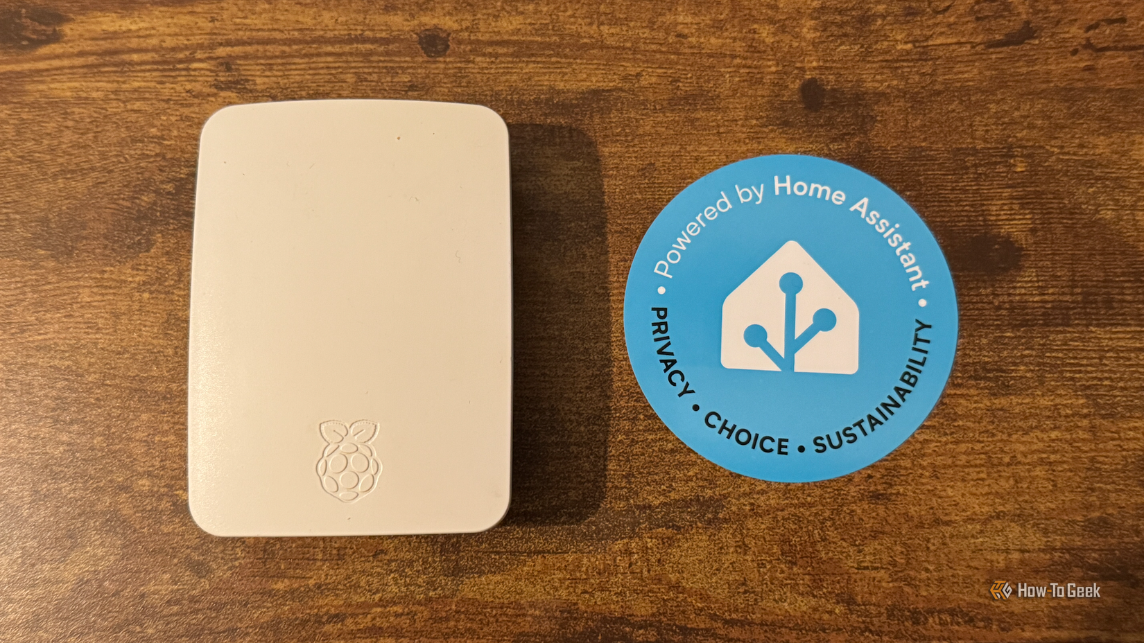 A Rasbperry Pi in an official Raspberry Pi case next to a Home Assistant sticker.