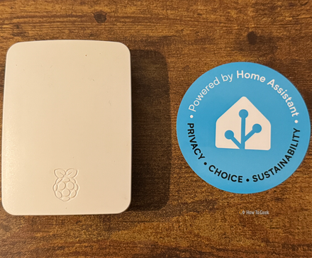 A Rasbperry Pi in an official Raspberry Pi case next to a Home Assistant sticker.