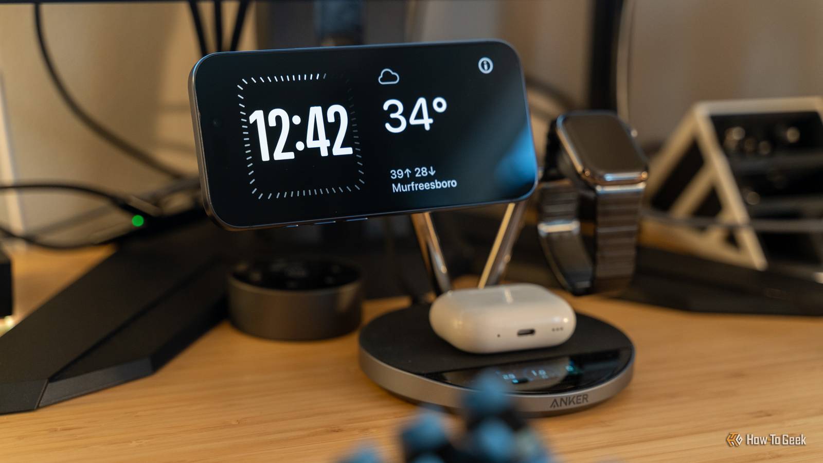 Anker's Prime Wireless Charging Station powering an iPhone 17 Pro, Apple Watch, and AirPods sitting on a wooden desk.