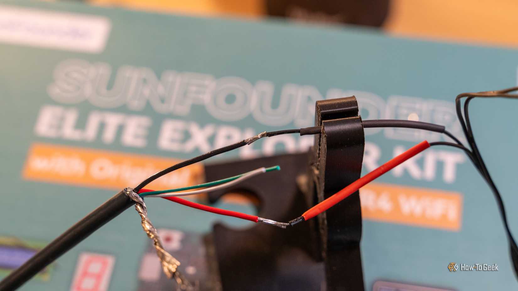 Red and black wires being soldered together with heat shrink tubing on one end.