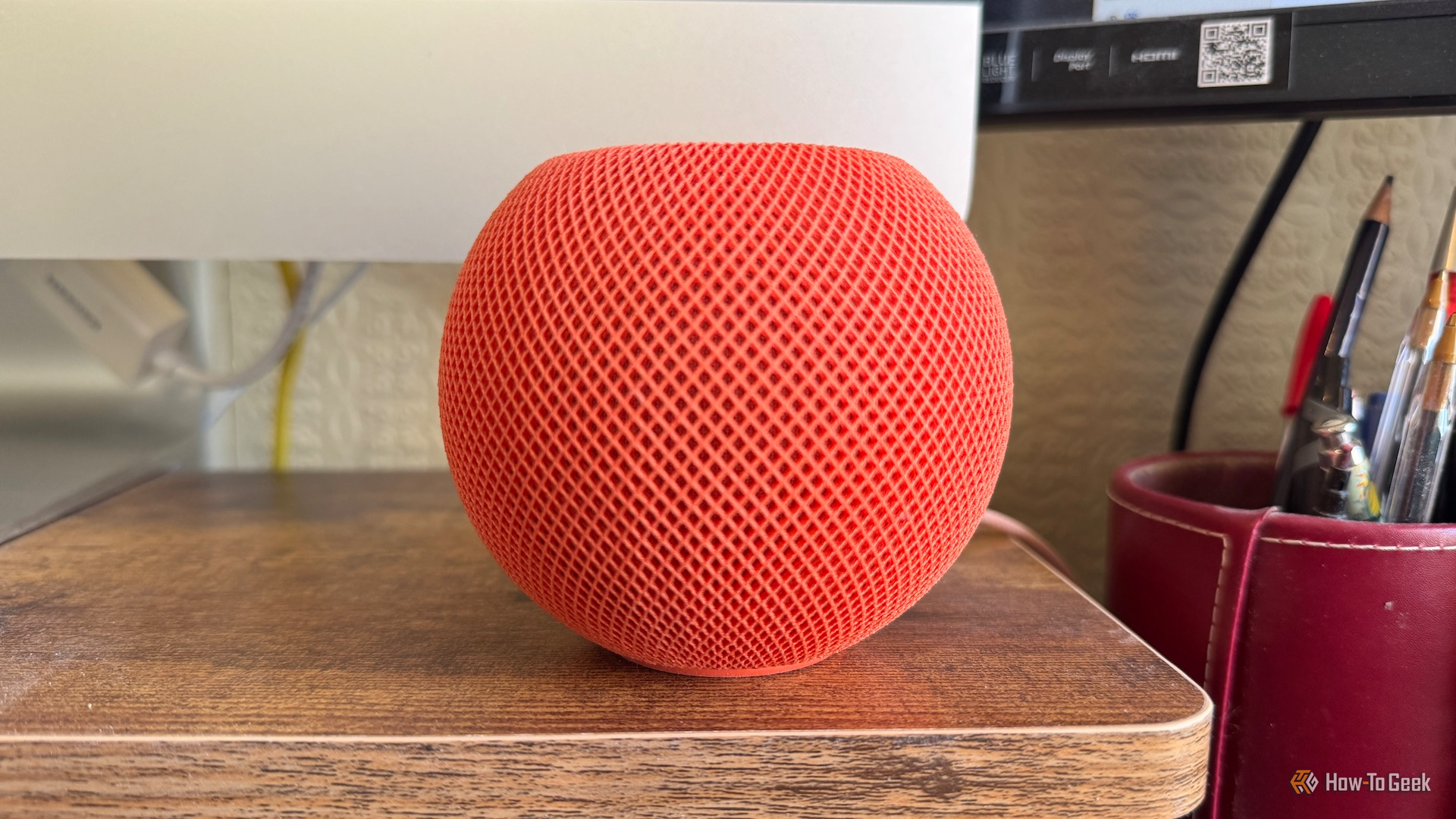 An Apple HomePod mini in front of an iMac screen.