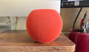 An Apple HomePod mini in front of an iMac screen.