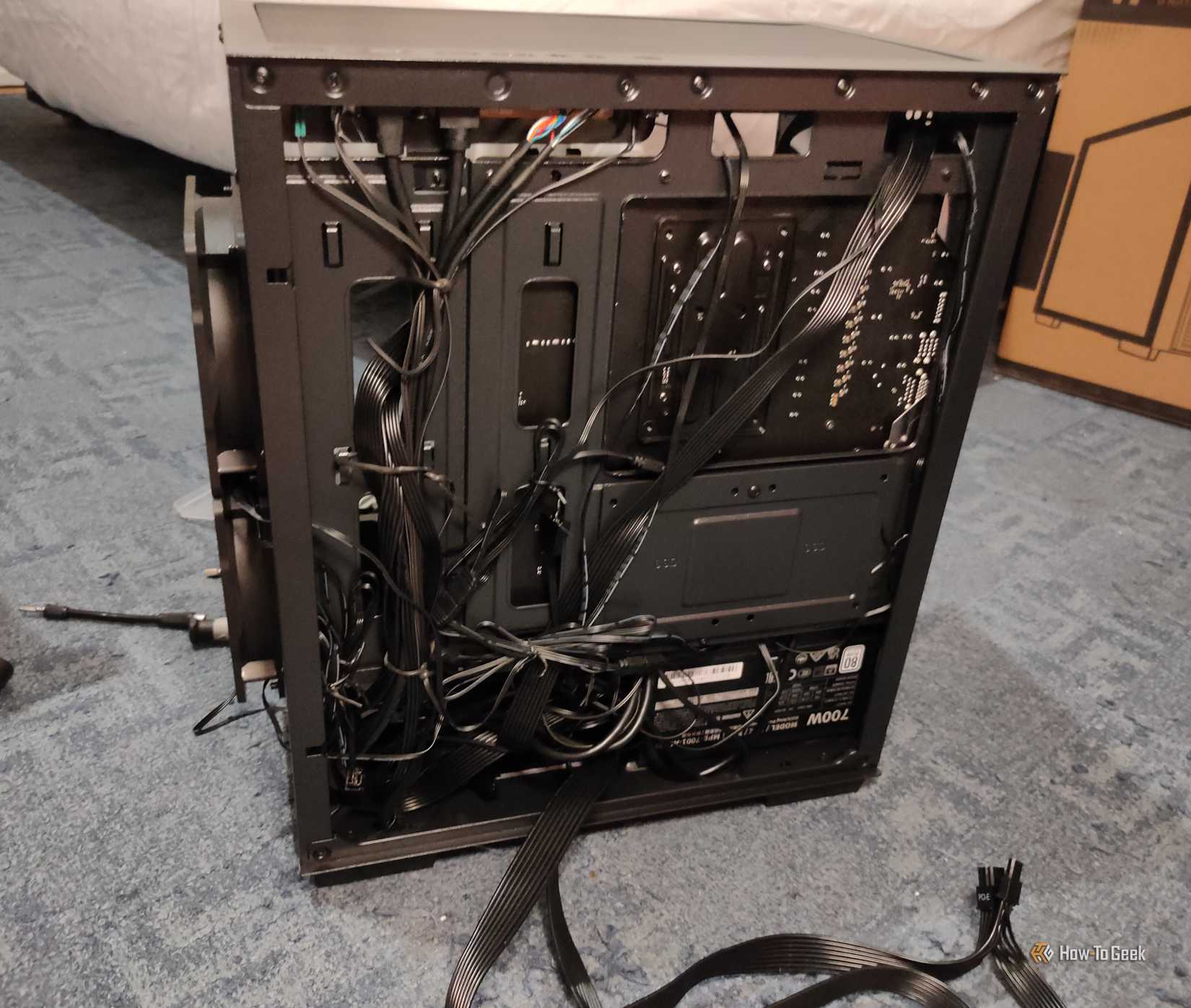 The back of a computer case with a lot of tangled cables.