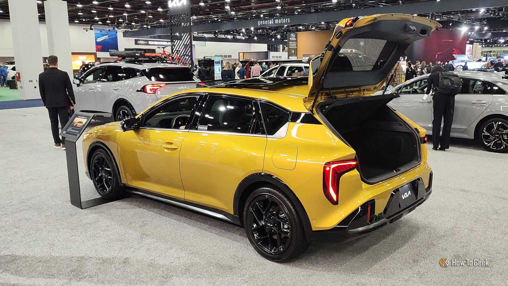 Plan 3/4 arrière statique d'une Kia K4 Hatchback 2026 jaune avec son hayon relevé.