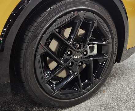 Close-up shot of the black alloy wheel on a yellow 2026 Kia K4 Hatchback.