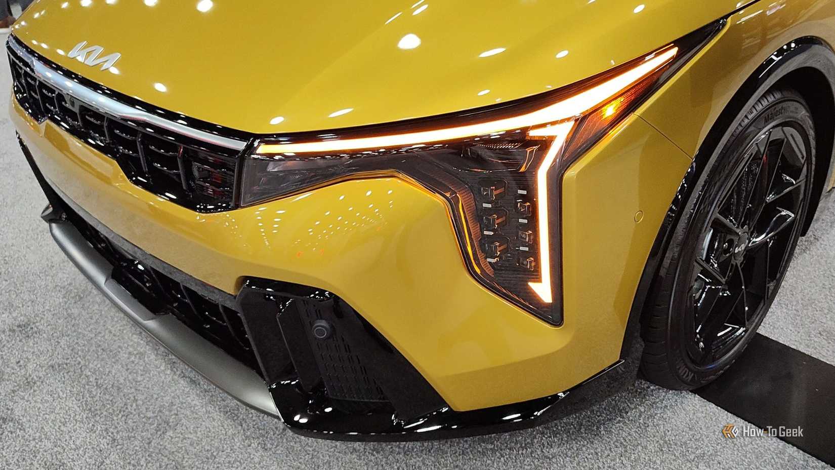 Gros plan du phare et de la calandre d’une Kia K4 à hayon 2026 jaune.