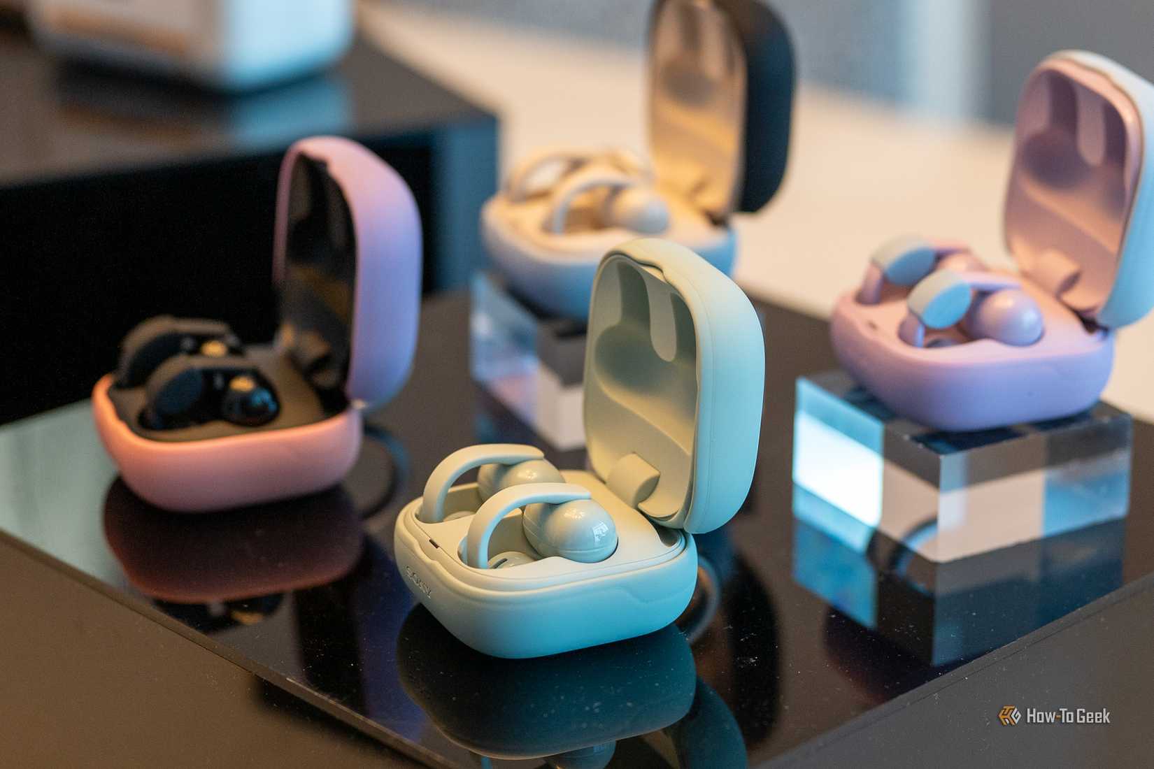 Sony LinkBuds Clip multiple colors sitting on a table with the charging case open.