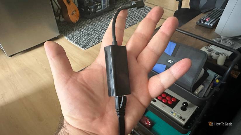 A hand holding an Ethernet cable connected to a USB-C adapter.