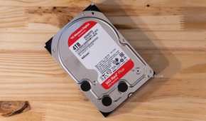 A Western Digital WD Red Plus 4TB NAS HDD sitting flat on a wooden desk.