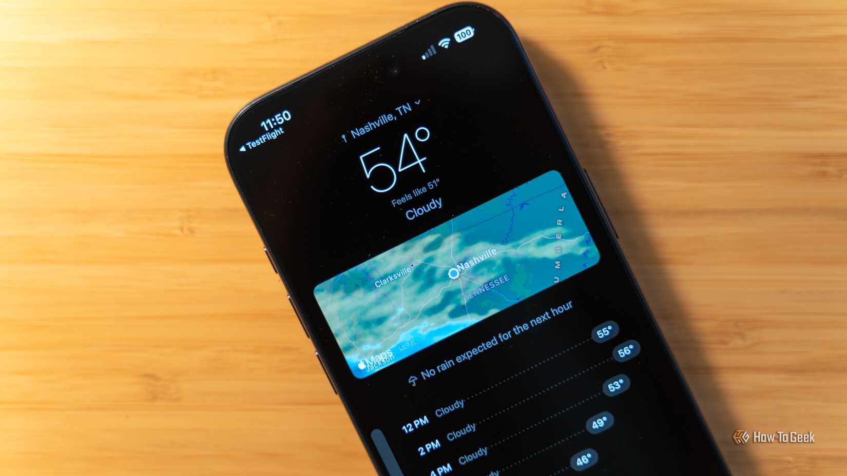 Um iPhone em uma mesa de bambu com o aplicativo meteorológico Unbrella em execução mostrando Nashville, TN.