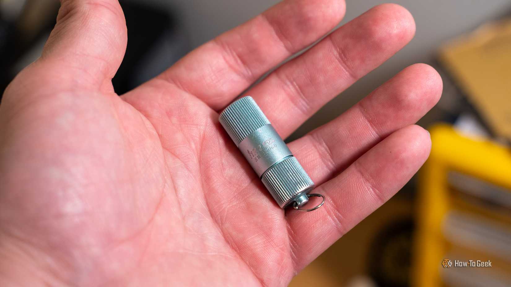 The OLIGHT I1R 2 LED flashlight held in one hand.