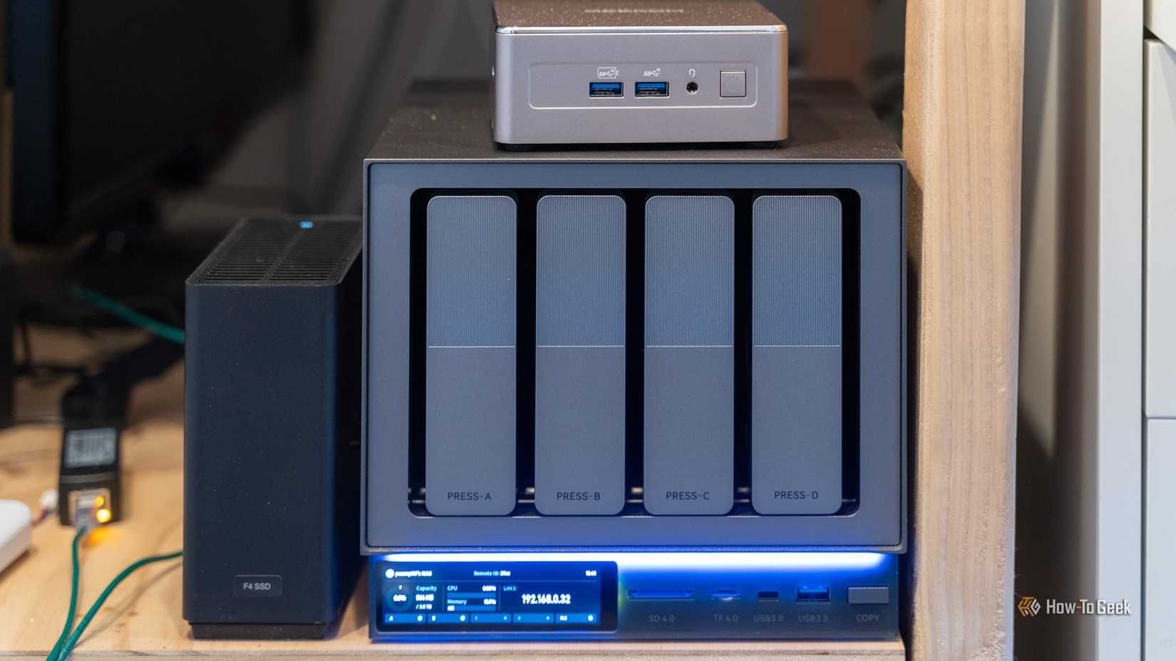 The Zettlab D4 NAS with a Geekom A5 mini PC and TerraMaster F4 SSD NAS on a wooden shelf.