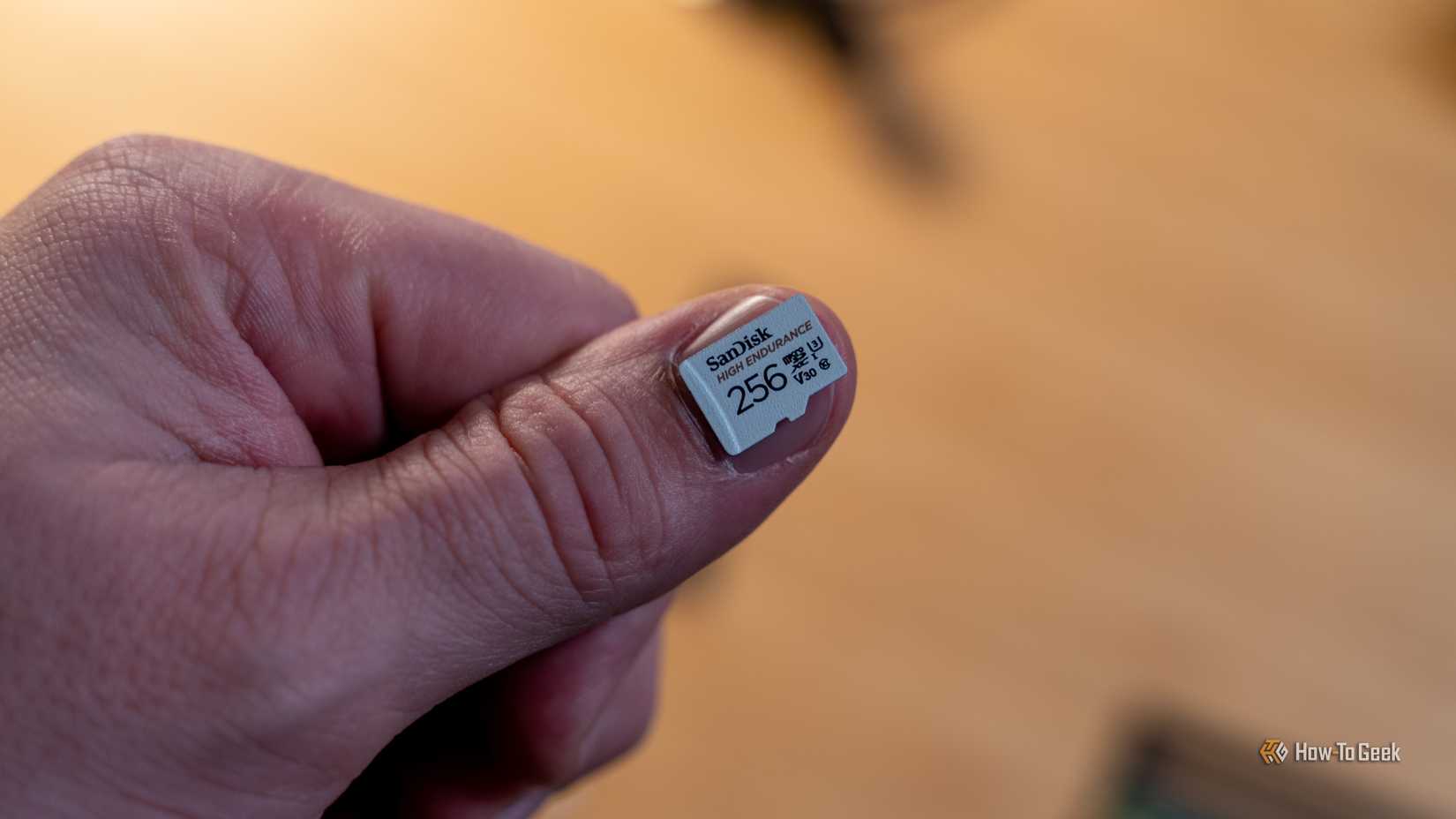 A 256GB microSD card sitting on a person's thumbnail.