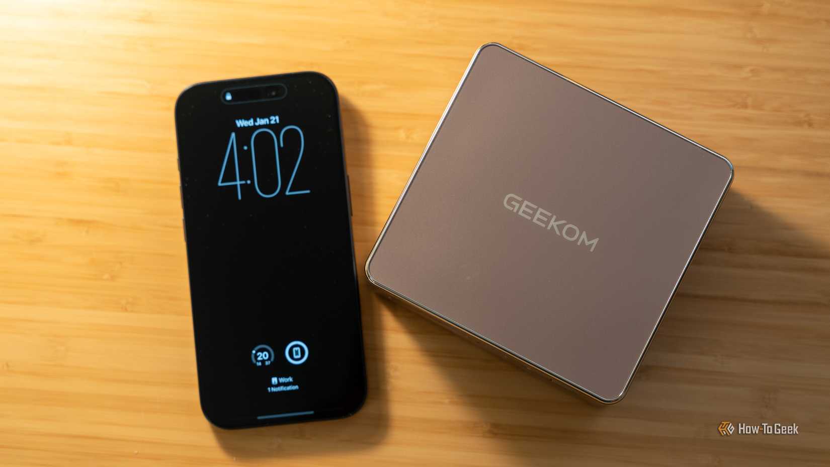 The GEEKOM A5 mini PC sitting next to an iPhone 17 Pro to show the size comparison.