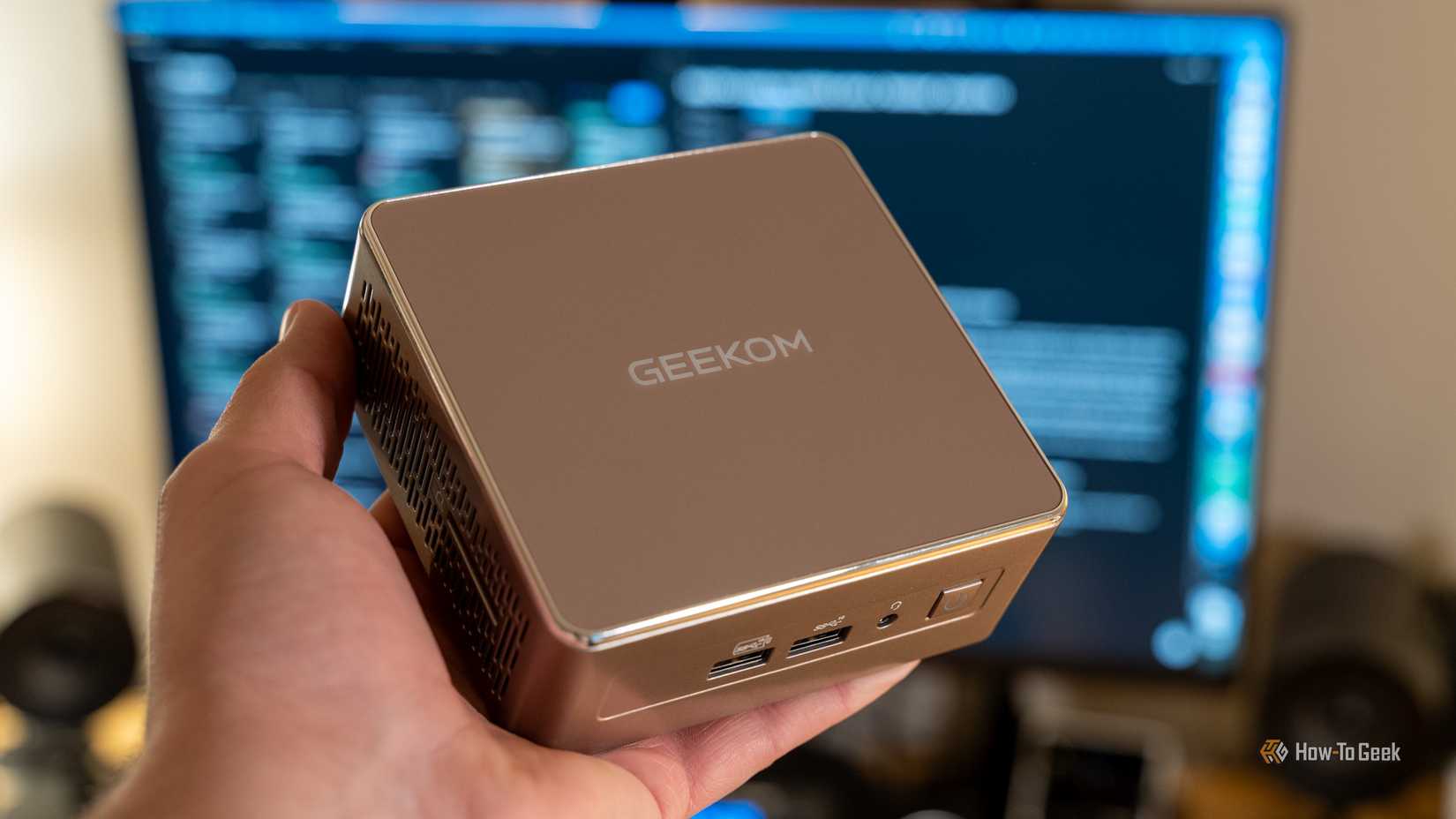 A GEEKOM A5 mini PC being held in a person's hand.