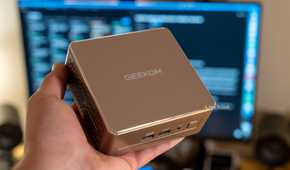 A GEEKOM A5 mini PC being held in a person's hand.