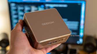 A GEEKOM A5 mini PC being held in a person's hand.