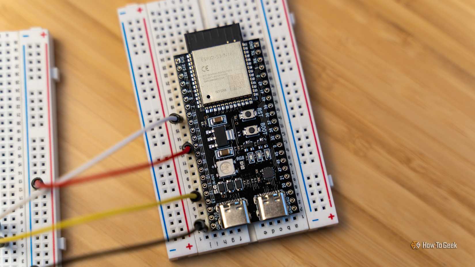 An ESP32 development board mounted to a breadboard with jumper wires connecting another breadboard.