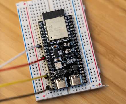 An ESP32 development board mounted to a breadboard with jumper wires connecting another breadboard.