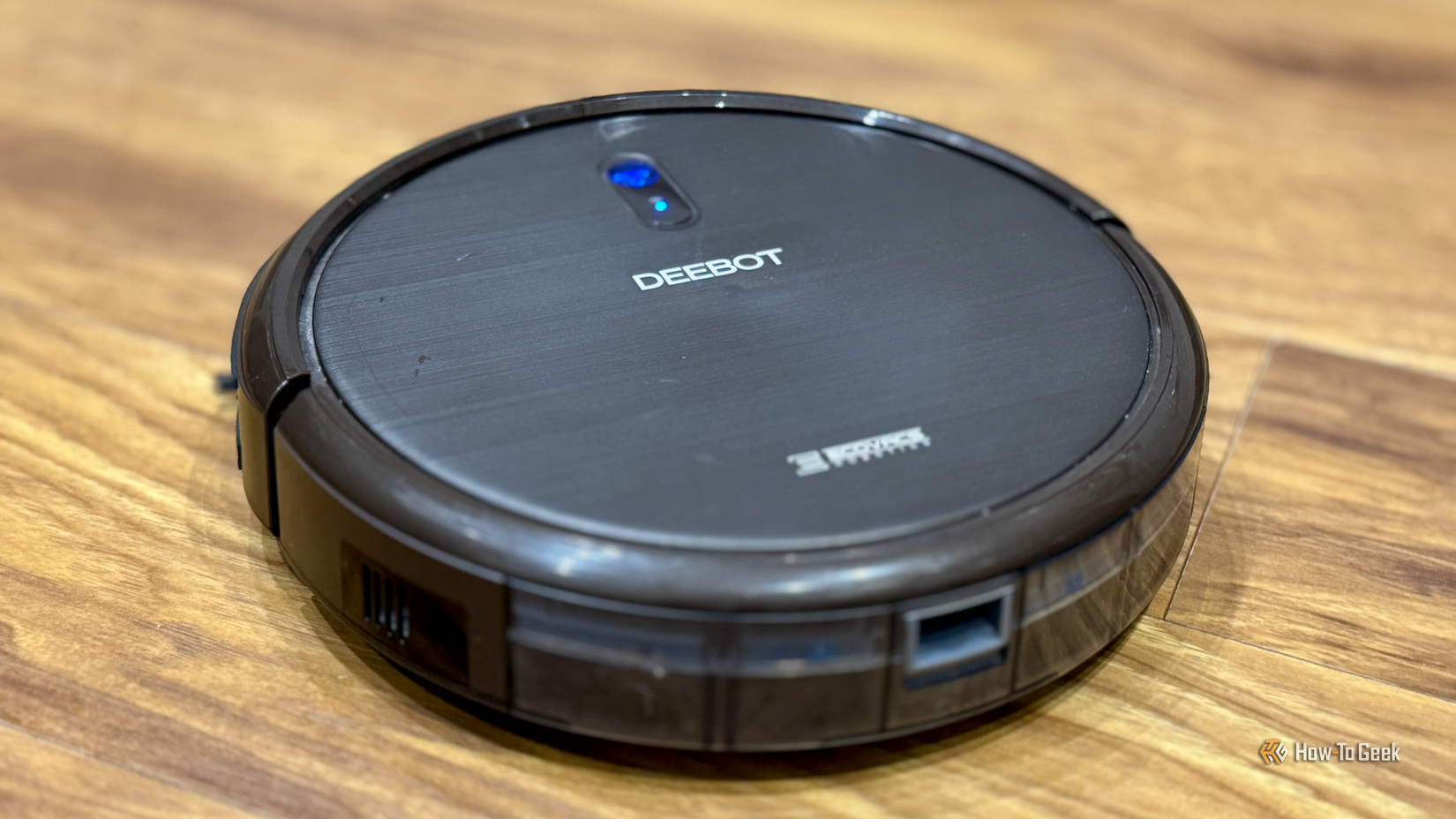 An Ecovacs Deebot N79S robot vacuum cleaner on a kitchen floor.