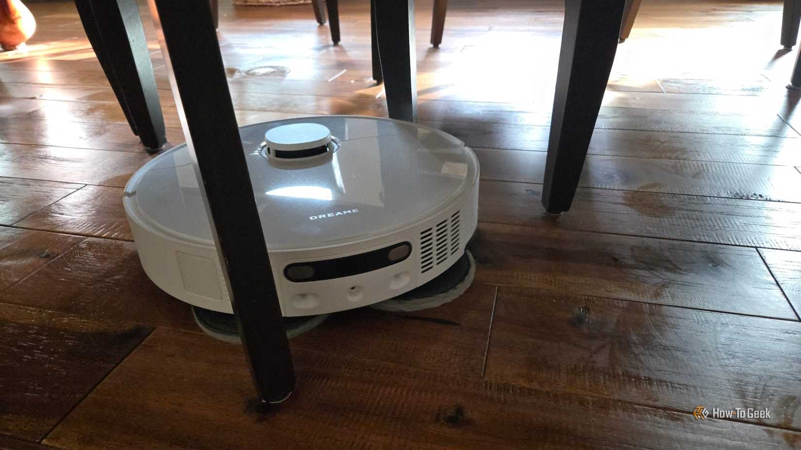 Dreame L40s Ultra robot vacuum cleaning under dining chairs.