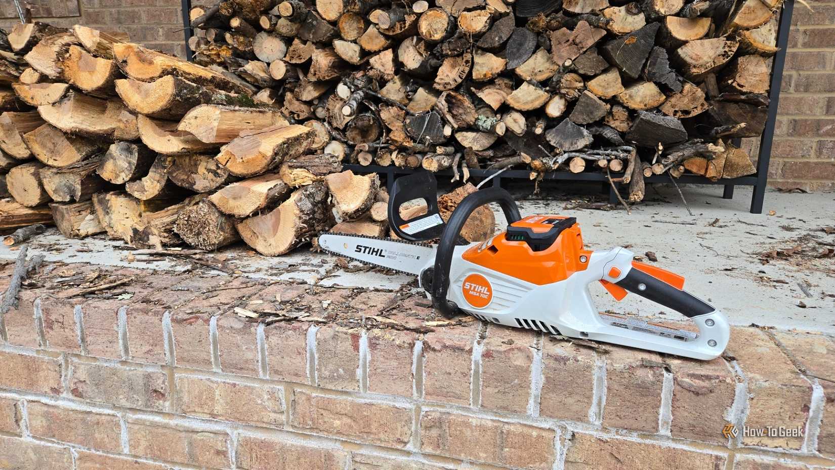 দুই গাদা ফায়ার কাঠের সামনে Stihl MSA 70C চেইনসো।