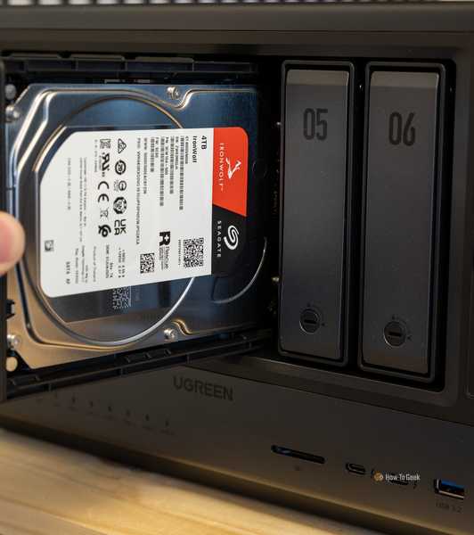 A hand inserting a Seagate IronWolf 4TB hard drive into the Ugreen iDX6011 Pro NAS with the IronWolf label visible.