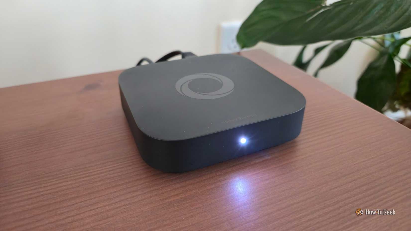 A Homey Pro Mini smart home hub on a TV stand.