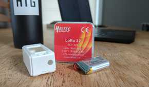 A LoRa 32 package with a case and a battery next to it.