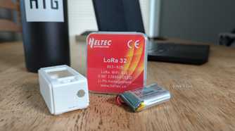 A LoRa 32 package with a case and a battery next to it.