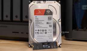 A Seagate IronWolf 4TB hard drive and a WD Black NVMe SSD side by side in front of the Ugreen iDX6011 Pro NAS.