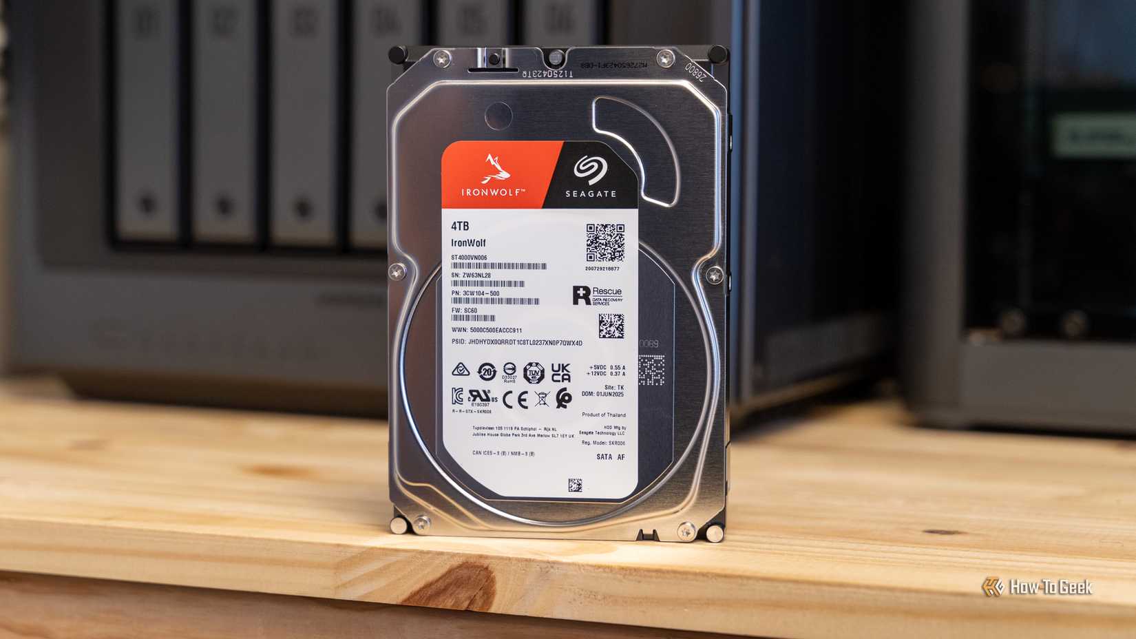 A Seagate IronWolf 4TB hard drive standing upright on a desk in front of the Ugreen iDX6011 Pro NAS.