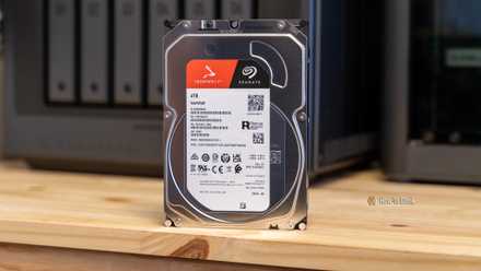 A Seagate IronWolf 4TB hard drive standing upright on a desk in front of the Ugreen iDX6011 Pro NAS.