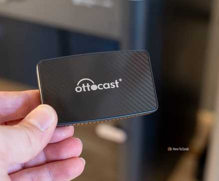 Беспроводной адаптер Ottocast для CarPlay в руке.