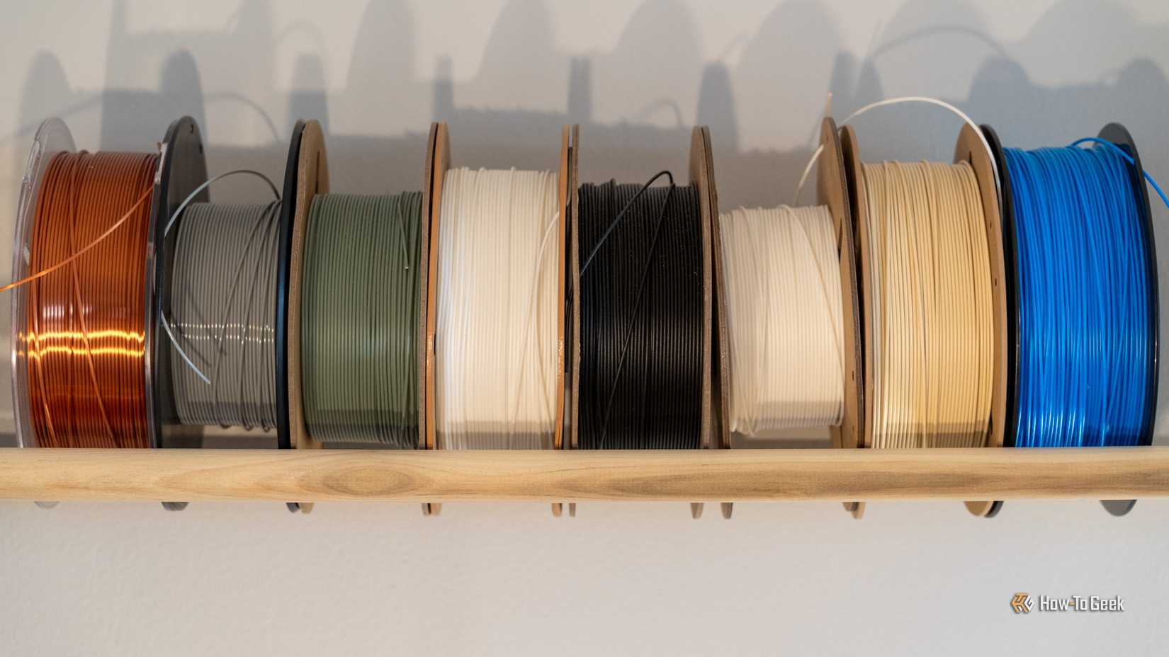 Filament rolls lined up against a wall showing multiple colors and types of filament.