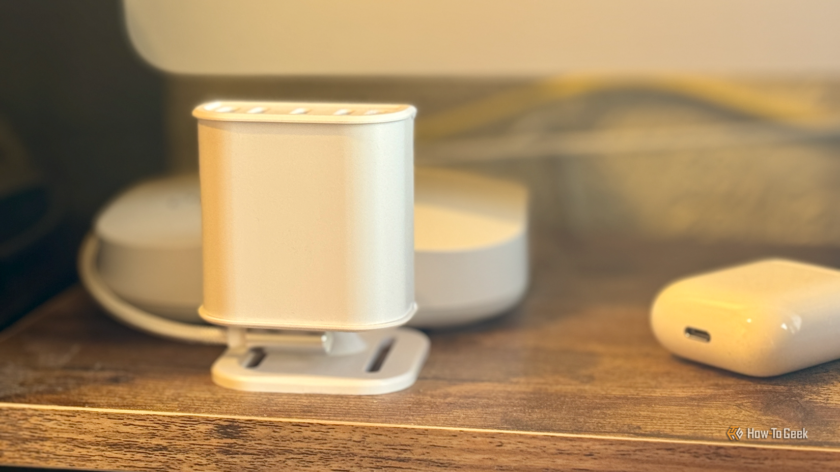 An Everything Presence Lite mmWave presence sensor on a monitor stand in front of a computer.